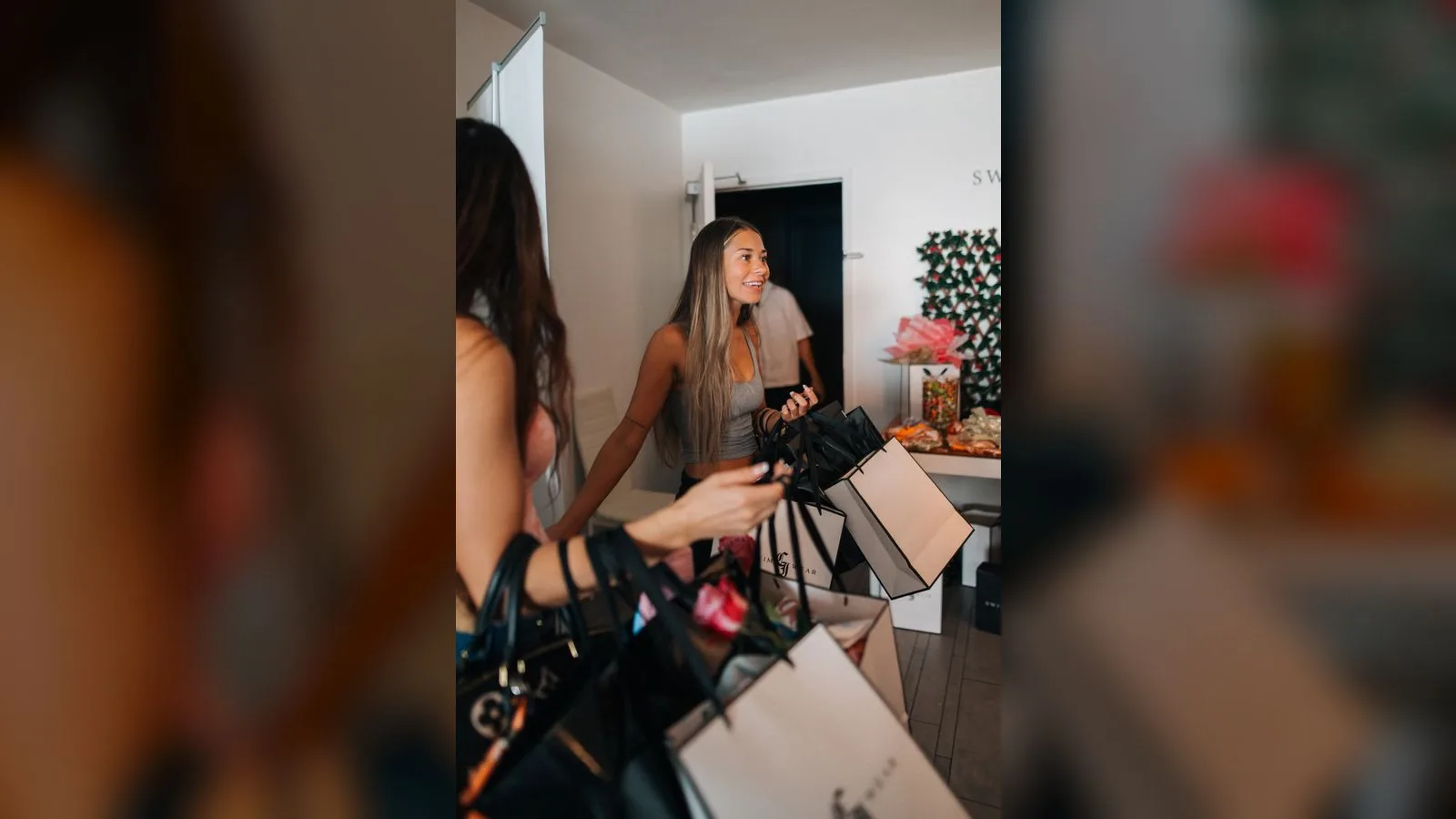 Two creators laughing together while gathering CI Swimwear branded gift bags in the studio