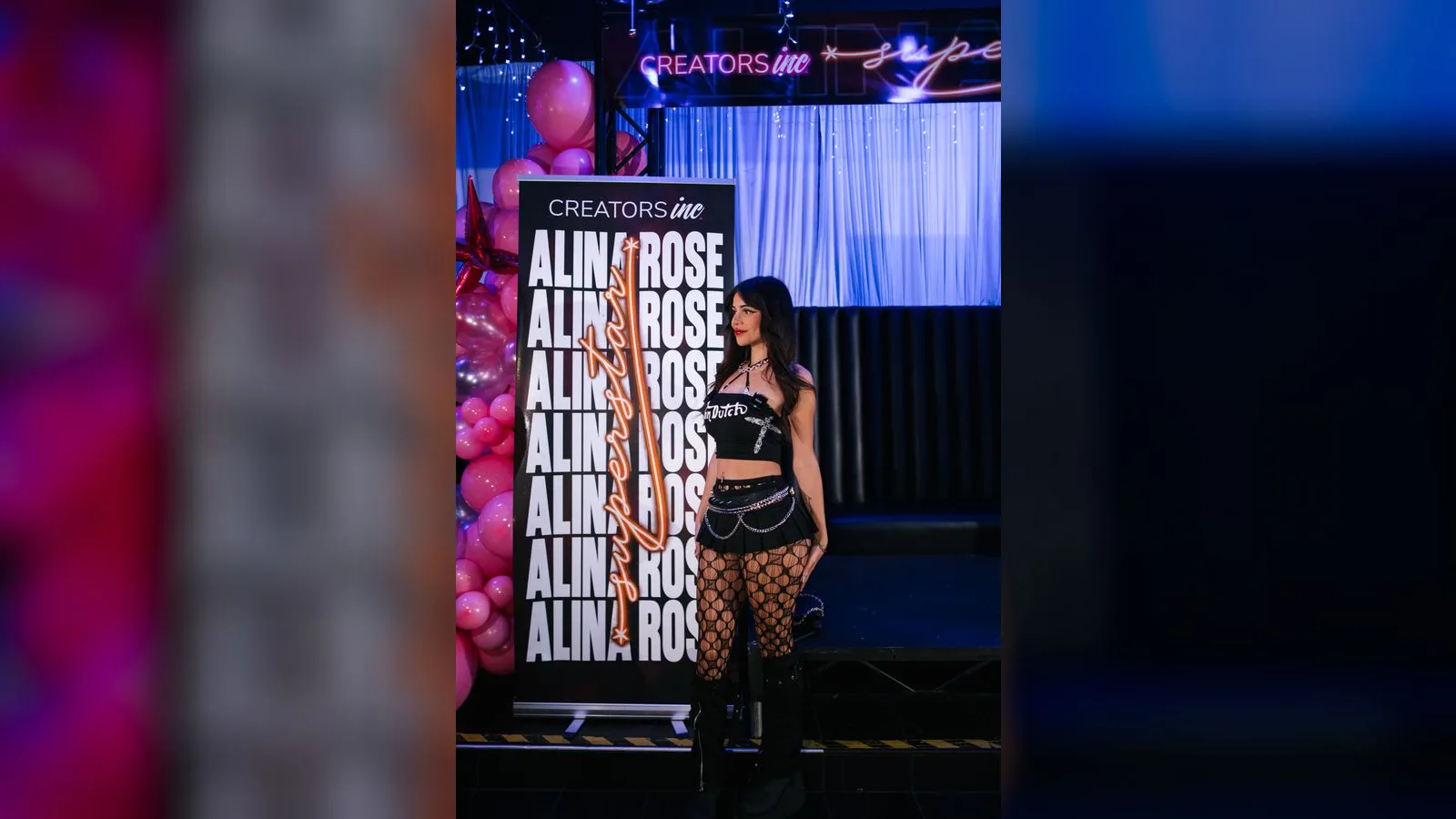 Artist standing beside the Creators Inc Alina Rose release party banner with balloon decor at the launch event