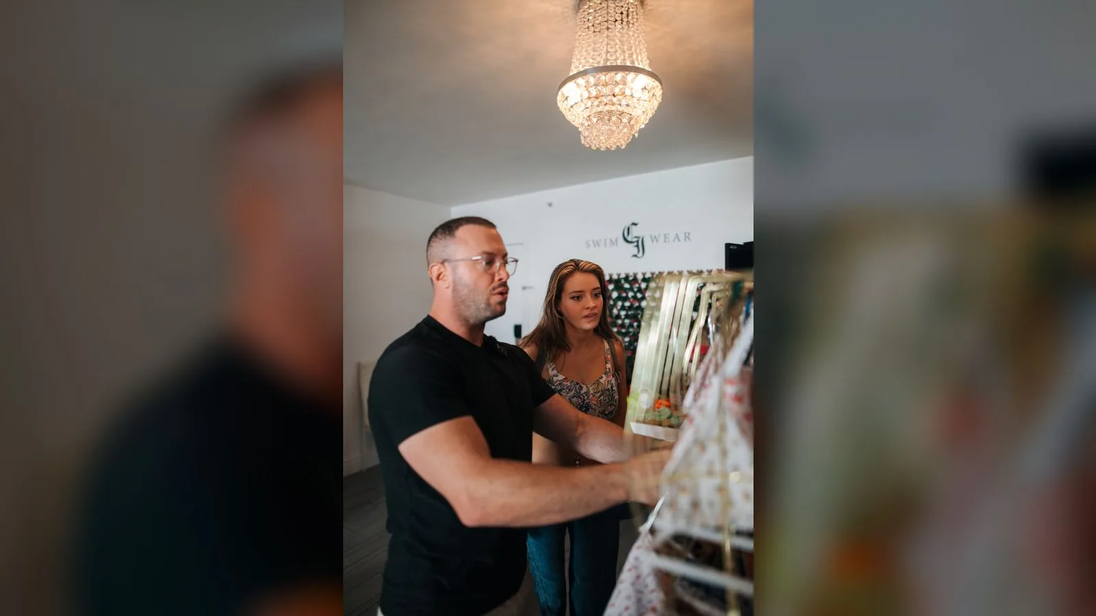 Founder and creator looking at swimwear pieces beneath a chandelier in the CI Swimwear showroom